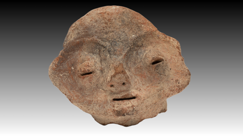 A face with two incised semi-circles for eyes, a triangular nose with perforated holes for nostrils and a horizontal incision forming a mouth. Two protrusions at either side of the eyes forming ears.