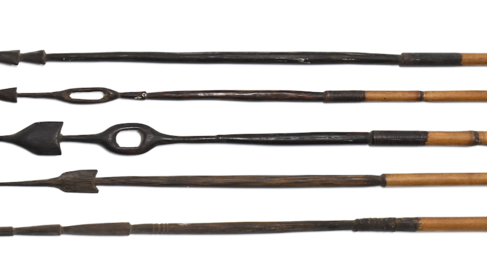 Five metal arrowheads with wooden shafts attached. Each arrowhead has a different appearance including elongated points and circular shapes with holes in the centre.