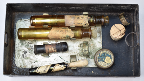 A metal tin containing glass vials with labels which include 'castor oil'amd 'olive oil'.