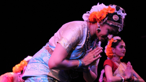 Dancers dressed in their costumes with their palms pressed together in front of their chests. The dancer in the foreground is bowing.