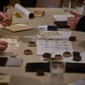 Three pairs of hands take part in a printing activity at a table within the museum galleries.