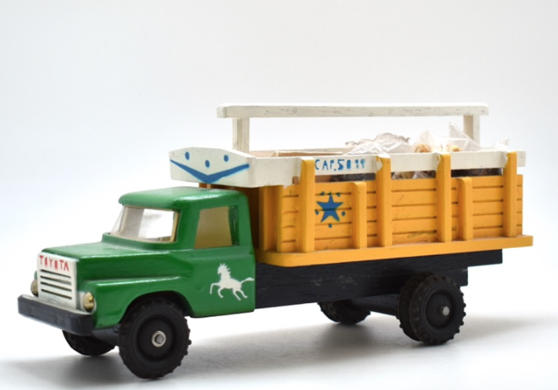 A model truck with its cargo of miniature bags of goods, plus a small ladder. The truck has a green cab and yellow open container. 