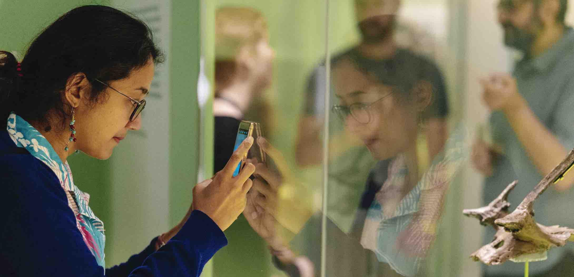 A woman taking a photo of a display during the opening of the exhibition Star Carr