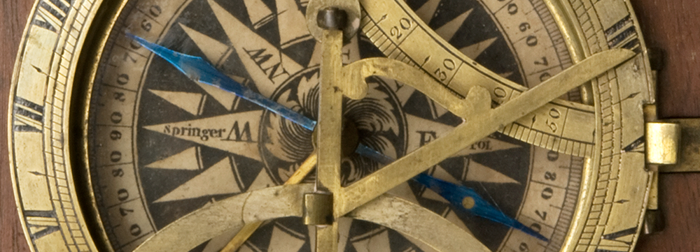 Detail of a Sundial and compass in mahogany case, close up showing metal details, reading 'springer' on one side, and a blue reader dial.