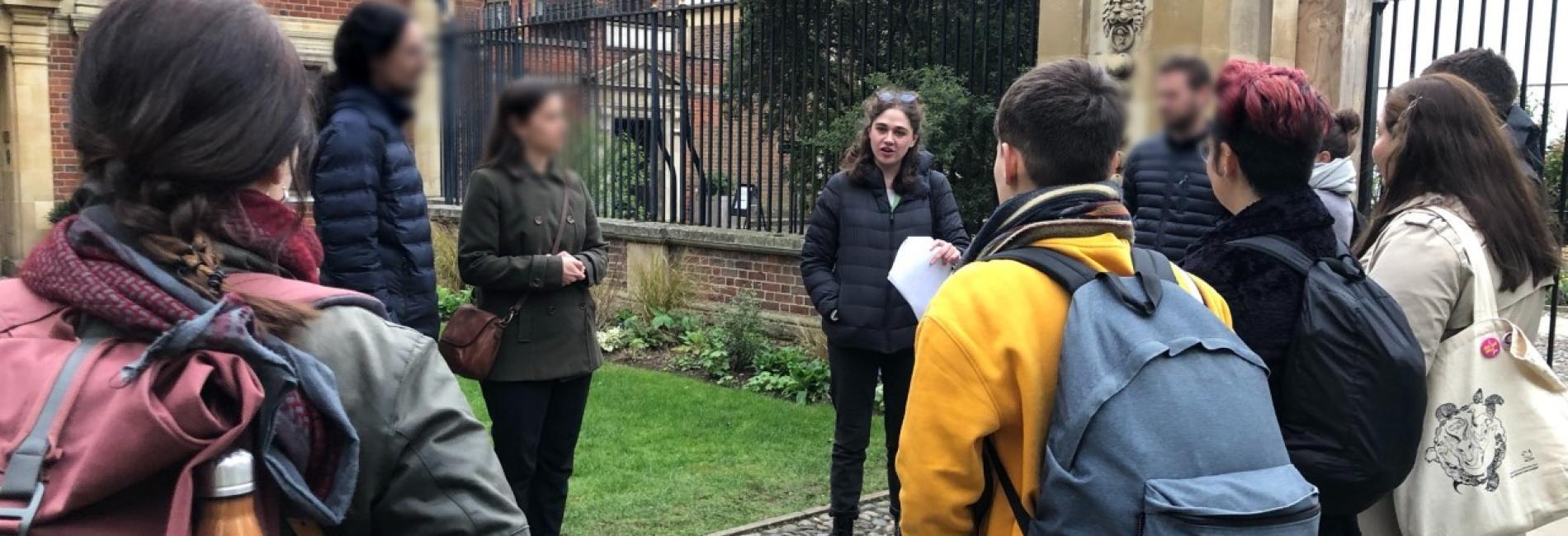 Cambridge and Empire Walking Tour - thumbnail A woman talks to a group of people standing outside, next to a college.