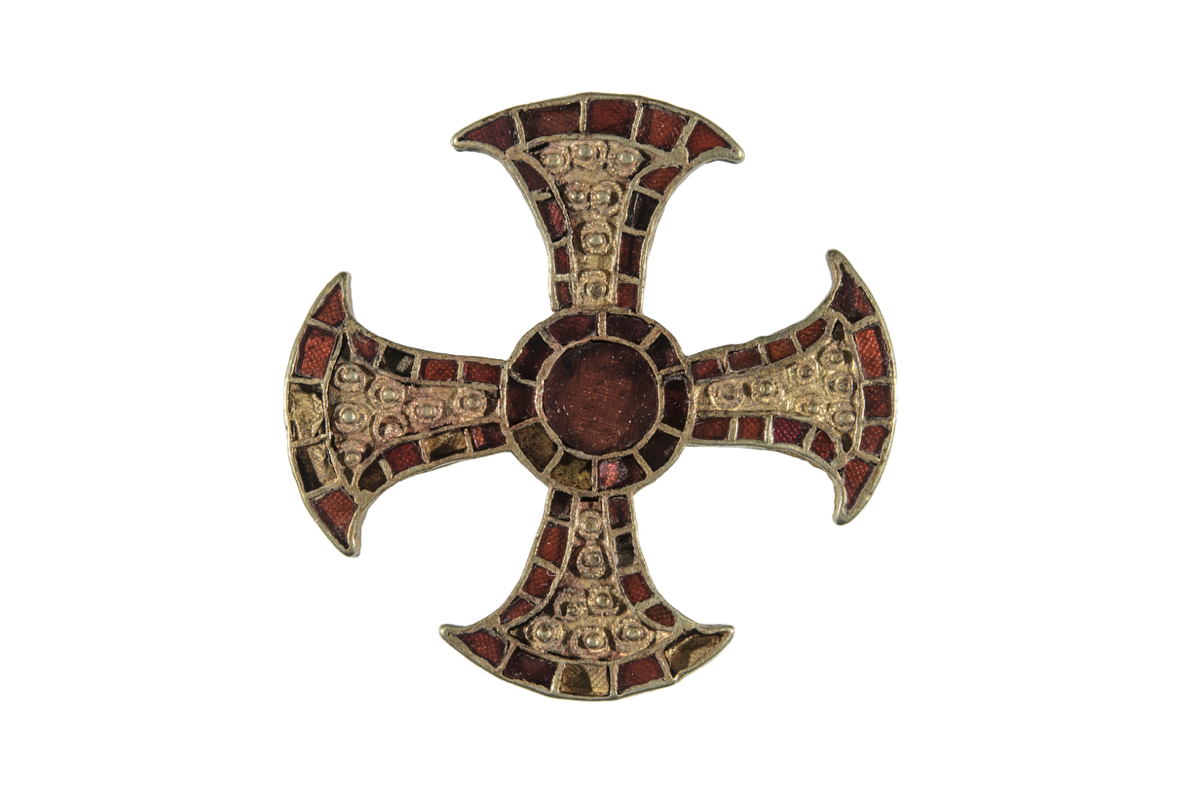 Gold cross decorated with flat-cut red gemstones. It has a central roundel and flaring arms. The centre of each arm has seven gold stud and wire ring-and-dot decorative protrusions..