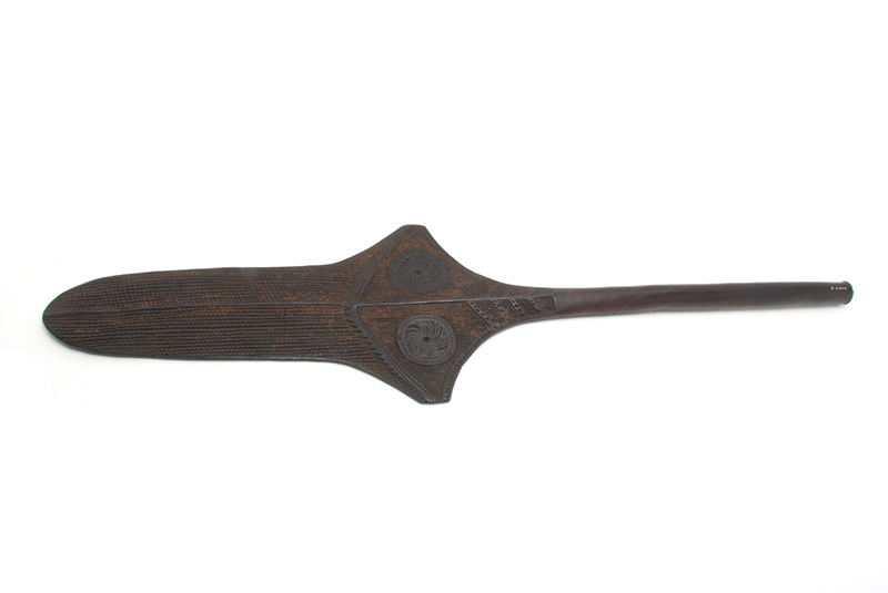 Flat, dark wood paddle club, the blade is decorated on both sides in relief.