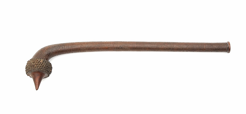 Dark wood club with a circular head curved off, with 8 rows of projecting spikes. The shaft is curved at the top and circular in section. It is finely carved all over.