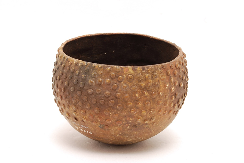 Unglazed ceramic round bowl with thick walls. Raised dots decorate the surface of the yellow-brown bowl.