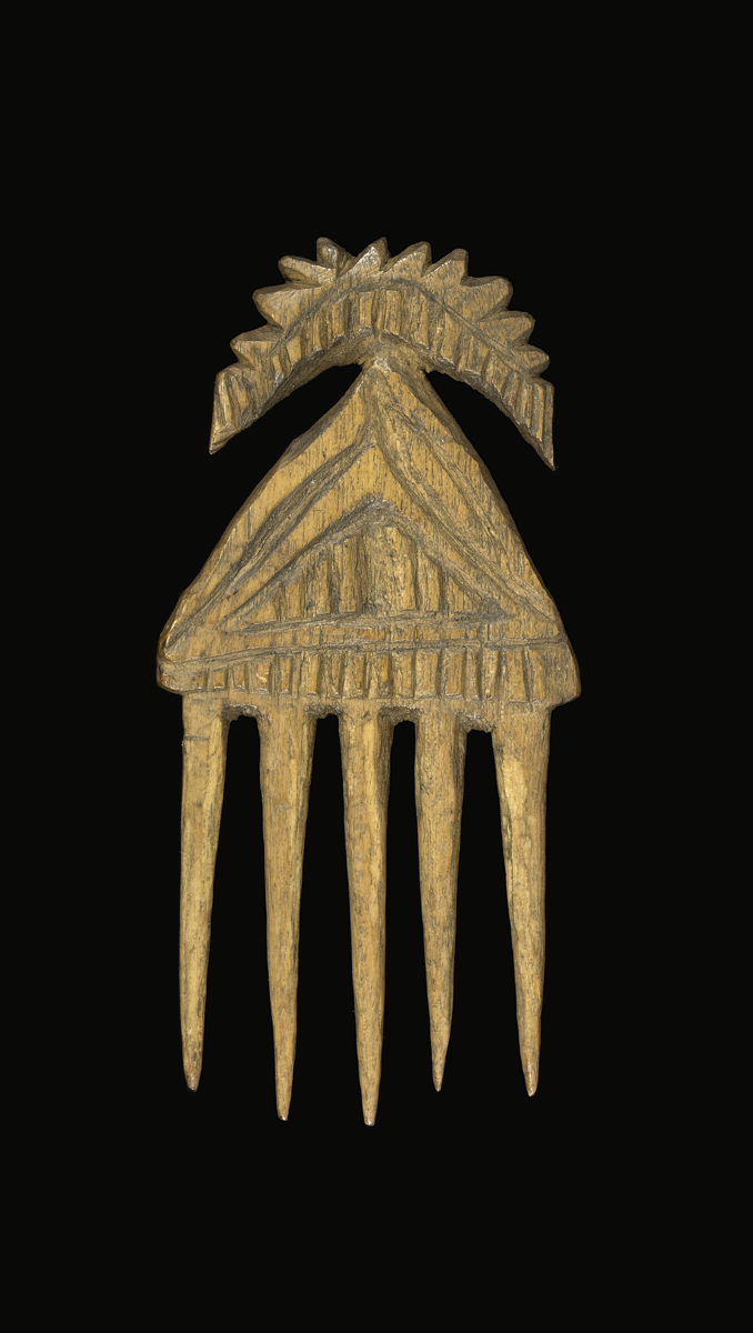 A comb carved from wood with five cylindrical and tapering prongs. Decorated with carved linear patterns on both sides.
