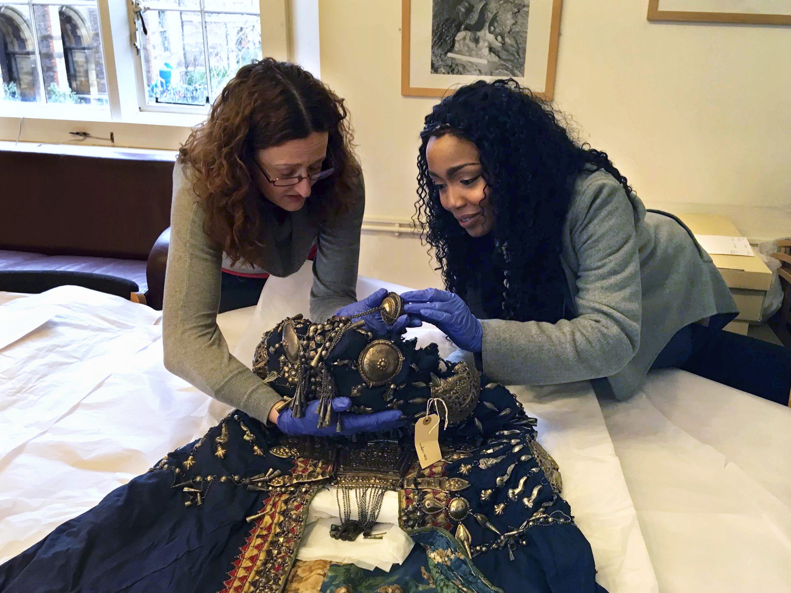 Researcher Vicky Ngari Wilson and Collections Manager for Anthropology Rachel Hand examining the robe of Abyssinian Queen Woyzaro Terunesh