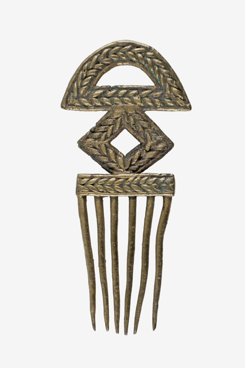 Oyiya. A brass comb with six long, tapering teeth. The handle consists of a semicircular top section with a cut out, followed by a rhombus shaped middle with a cut out and an elongated rectangle at the base.