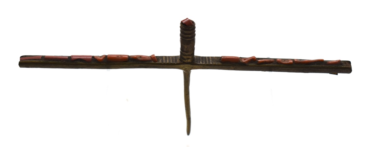 Hair ornament, long piece of brass inset with coral, pin at right angles to centre. There is a central cylindrical projection with a piece of coral set into the top.