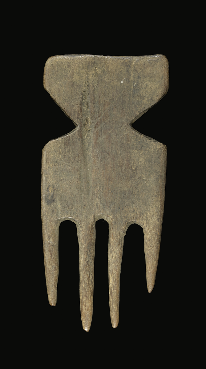  A comb carved from wood with four large and spaced out prongs. The prongs are cylindrical and taper to a worn point. The handle is rectangular with a small triangular cut-outs at each side, forming a constriction.