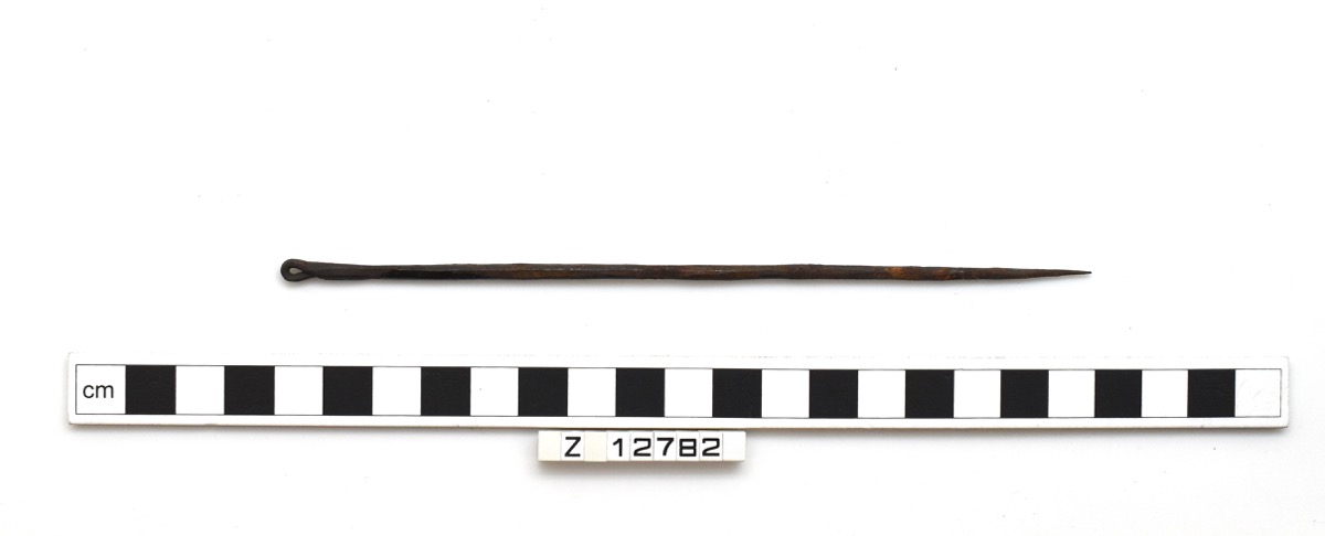 Hairpin formed of a long, faceted rod. Laid against a measuring guide showing it to be around 17cm long.
