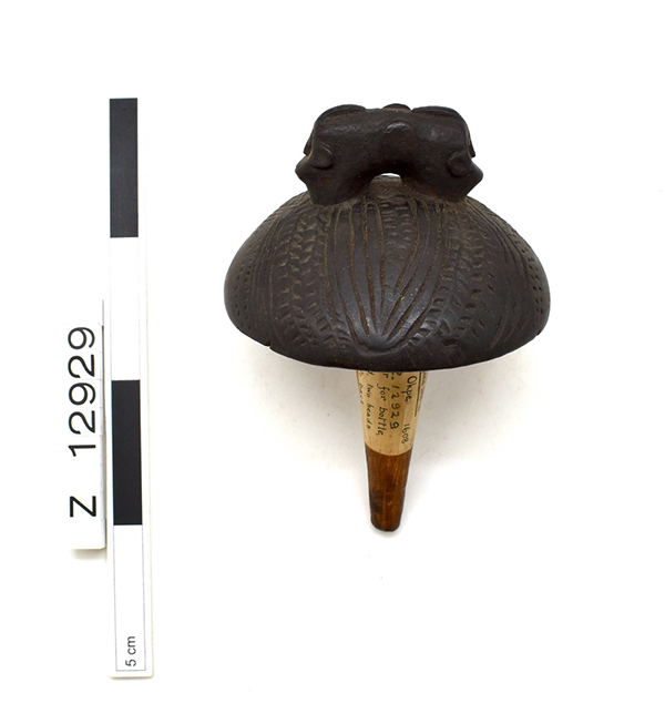 Bottle stopper. Rounded top with two back-to-back heads. Dark brown.