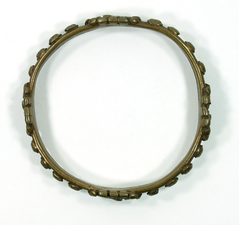 Brass bracelet decorated with raised projections and four stylised human heads.