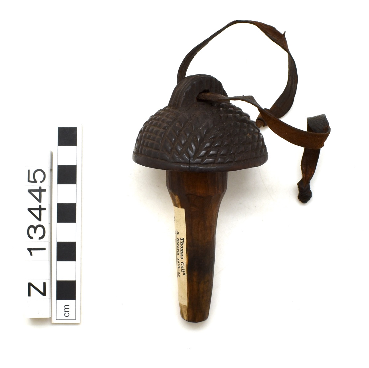 Bottle stopper with a rounded top and curved handle. Rippled designs on the top, which is cone-like in shape. A leather handle with open ends is looped through the handle.