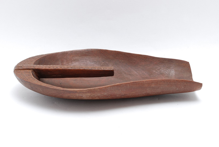Canoe bailer carved from a single piece of dark wood. Handle of almost rectangular section, the top of which incised with geometrical motifs (striated triangles and bands of zigzags). 