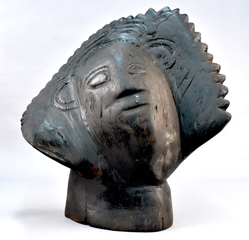 Star Girl sculpture. A silvery-grey wooden sculpture of a human head. Incised suggestion of eyes, nose, mouth and ears