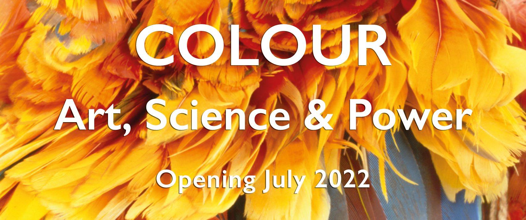 Banner with the words 'COLOUR: Art Science and Power / opening July 2022' against a zoomed in, brightly coloured image of a feathered headdress, in bright reds, yellows and blues.